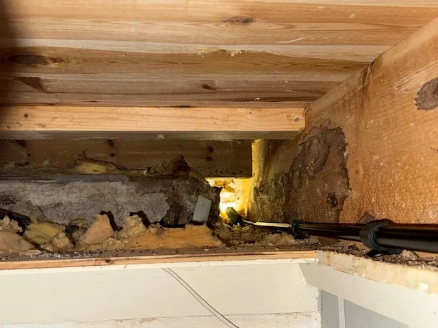 Foto inne i etasjeskiller i Nedenes som viser blottlagt treverk og isolasjon etter fjerning, med synlige spor av tilgrising